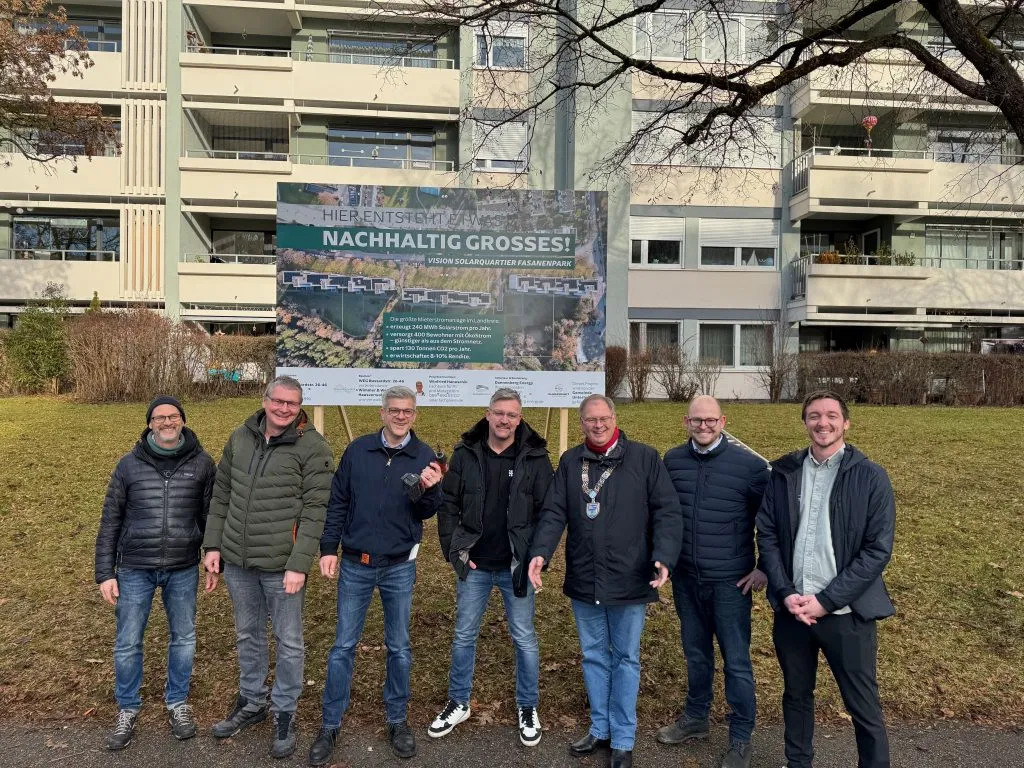 7 Männer stehen vor einem Mietshaus in einer Reihe