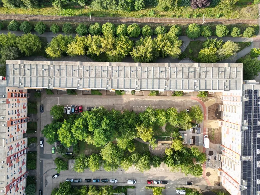 Luftansicht dreier Mehrfamilien-Häuserblocks in einer U-Anordnung mit einem begrünten Innenhof und grüner Umgebung